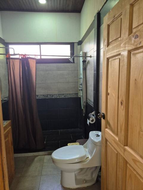 Baño con tina, cortina café y acabados en madera