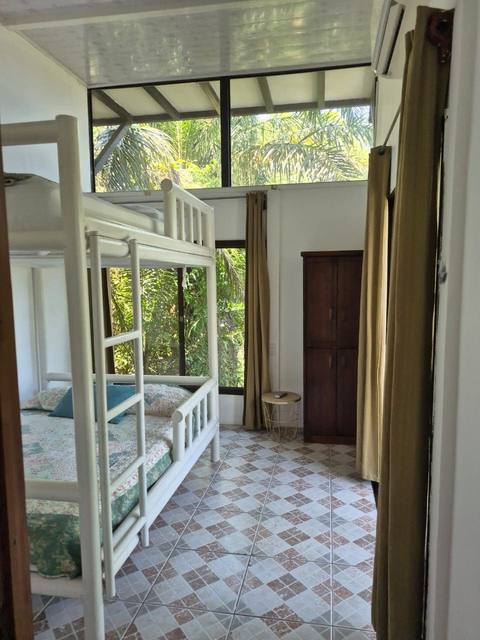Interior con armario de madera y ventanales altos hacia la selva