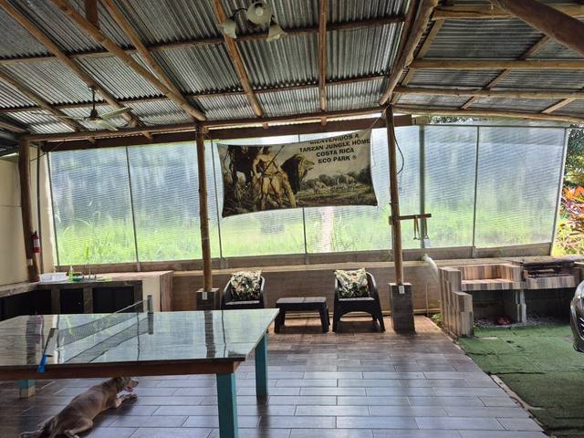 Área social del rancho con parrilla y mesa de ping-pong, con la manta de bienvenida a Tarzan Jungle Home Costa Rica