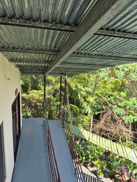 Balcón techado en la Casa Familiar Segundo Piso, con vista al puente de canopy entre los árboles