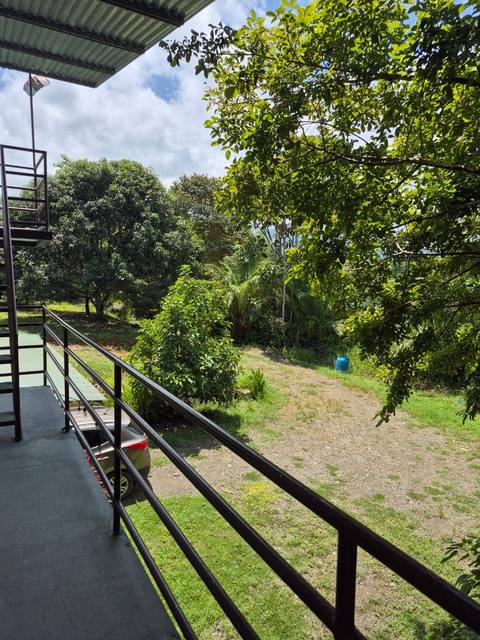 Vista desde el balcón hacia el jardín, el parqueo y la selva