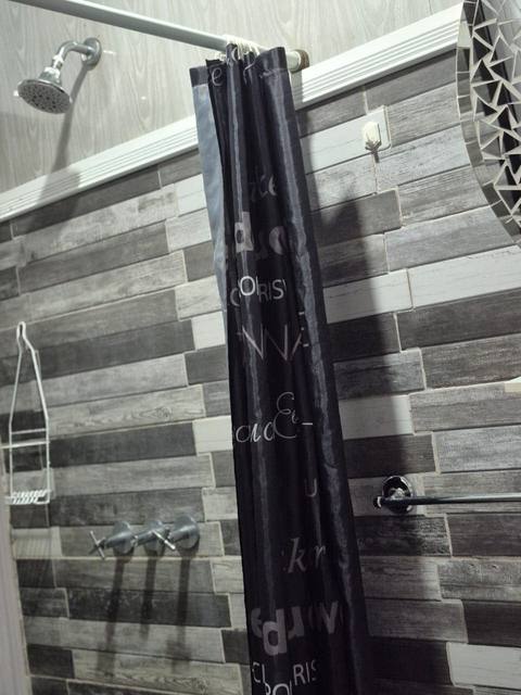 Detalle de la ducha con cortina estampada en el baño de la Family Tree House