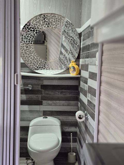 Baño con espejo circular de mosaico sobre el inodoro
